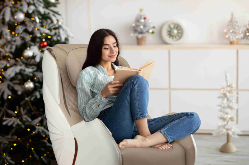 Stay home pastimes. Millennial Indian woman sitting in cozy armchair with open book indoors. Beautiful young lady reading exciting story, enjoying lazy morning, having relaxing weekend