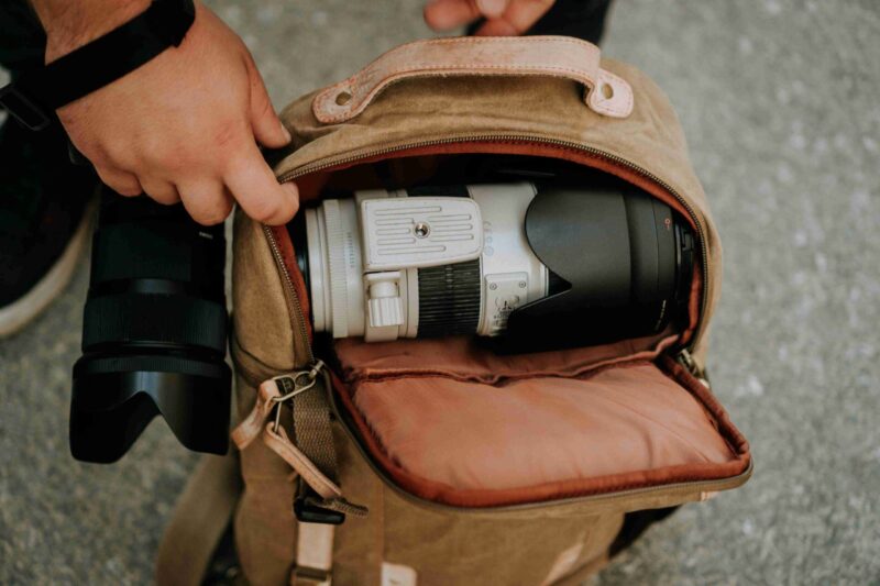 A photographer taking out a white camera lens from a camera bag