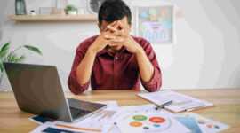 Man working with laptop and paperwork with stress