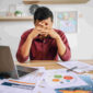 Man working with laptop and paperwork with stress