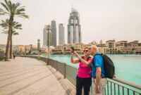 happy senior couple on sightseeing trip at dubai lake taking selfie