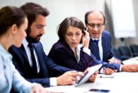 Businessmen and businesswoman confer. Businessman holding digital tablet.